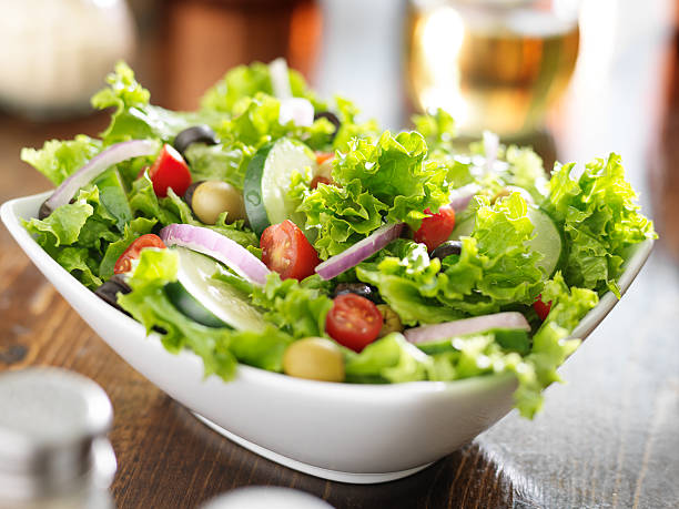 big bowl of salad bowl of leafy green salad with olives, tomatoes and cucumber. salad stock pictures, royalty-free photos & images
