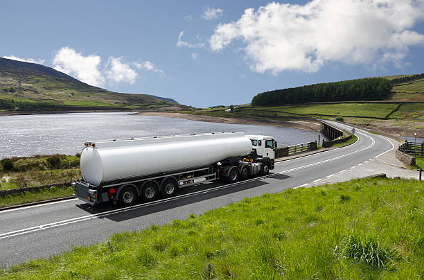 große gas-tanker truck auf scenic highway mit see - tanklastwagen stock-fotos und bilder