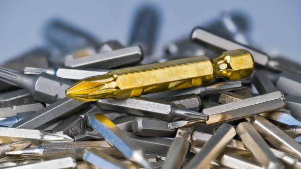 Big golden cross screwdriver bit on silvery bits heap of various sizes and types stock photo