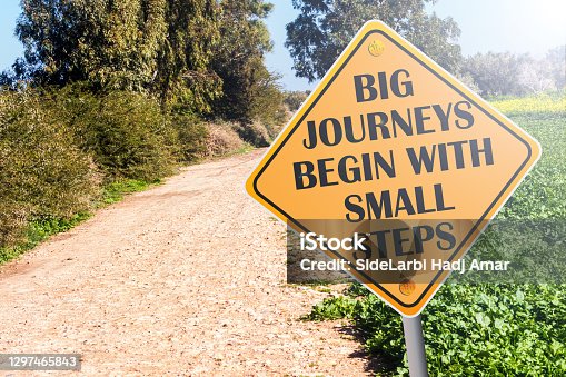 istock Big Journeys Begin With Small Steps sign on road 1297465843