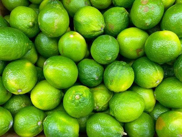 big pile of fresh lemons limes stacked at fruit stand farmers market grocery store stock photo