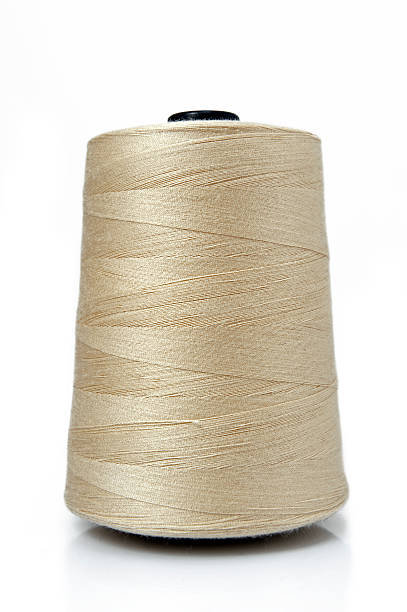 A big spool of gold sewing thread stock photo