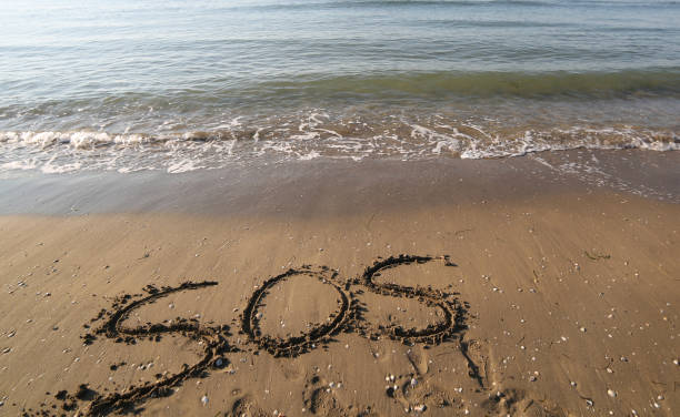 big text SOS on the sand of the beach stock photo