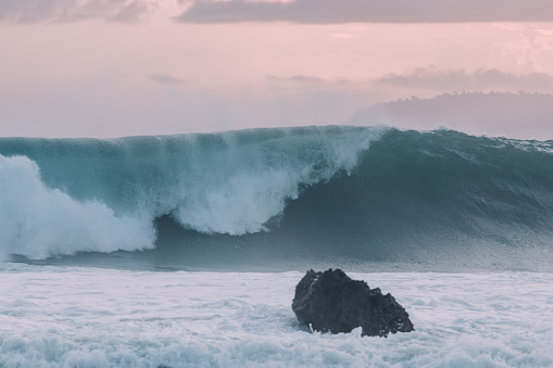 Big wave breaking with a rock in front of it