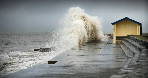 A big wave smashing into a dock in a storm stock photo