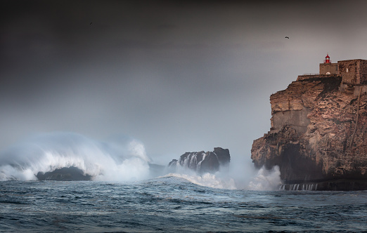 Stunning Image of giant wave crashing into cliff and lighthouse  after major Atantic Storm.