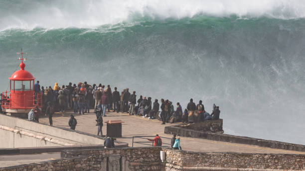 Biggest Wave In The World, Nazare, Portugal Stunning, unbelievable, Image of giant wave crashing into cliff and lighthouse  after major Atantic Storm. big wave surfing stock pictures, royalty-free photos & images