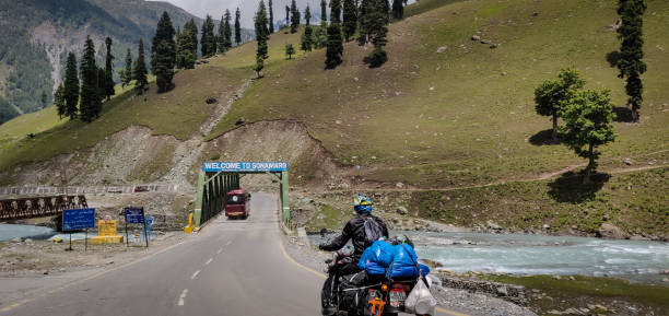 A biker entering the Sonmarg region through it's bridge. Sonmarg, Jammu and Kashmir - June 18 2019: A biker entering the Sonmarg region through it's bridge. srinagar stock pictures, royalty-free photos & images