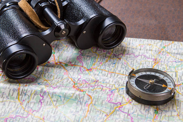 Binoculars and compass on map. Binoculars and compass on map. Compass lying on a map. Choose the best route. These things belong to captain. territorial animal stock pictures, royalty-free photos & images