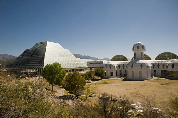 Biosphere 2 in Late Afternoon Light "Reflecting the beauty of late afternoon sunlight off its 6,500 panes of glass, Biosphere 2 rests quietly in the desert.  It is an extensive science research facility originally created to study the interaction between Earth's life systems in a closed environment.  Two separate missions were initially launched with scientists sealed within the vivarium for up to two years.  They studied five different biomes: rainforest, ocean with a coral reef, mangrove wetlands, savannah, and desert.  The complex is now run by the University of Arizona and is considered a place where research, teaching and studying the Earth's living systems can be accomplished in the world's largest closed system ever created." biosphere 2 stock pictures, royalty-free photos & images