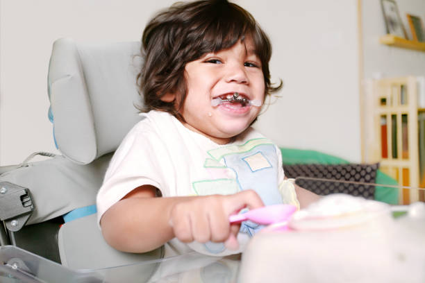 Biracial Disabled litle boy sitting in wheelchair smiling stock photo