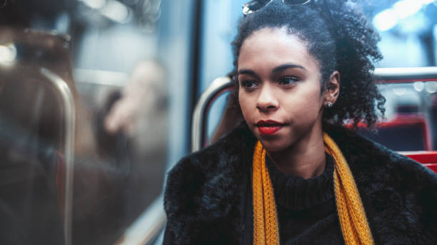 Biracial female in a metro carriage A young charming African-American curly-hair female in a yellow scarf is sitting in a car of a subway train and pensively looking out the window, with a copy space area on the left for advert text hot latino girl stock pictures, royalty-free photos & images
