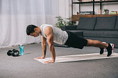 bi-racial man doing push ups in sportswear on  fitness mat