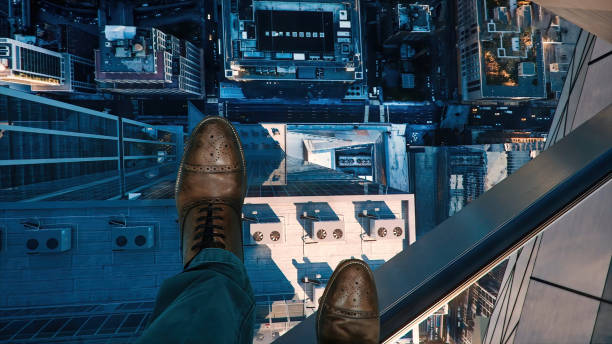 Bird's eye view from the clear glass deck on top of a high rise building Bird's eye view from the clear glass deck on top of a high rise building. In the photo are the legs of a man in elegant shoes. foot center stock pictures, royalty-free photos & images
