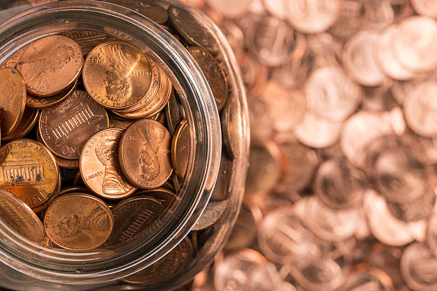 Birds eye view of penny jar overflowing A jar of pennies surrounded by pennies. coin stock pictures, royalty-free photos & images