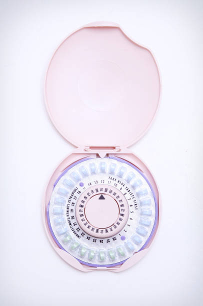 Birth Control Pills and Container on White Background The hormones/chemicals norgestimate ethinyl estradiol in pill form; isolated on white in a pink container.  Vertical with copy space. birth control pill stock pictures, royalty-free photos & images