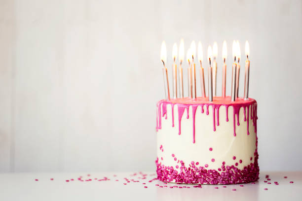 Birthday cake with pink drip icing and candles Birthday cake with pink drip icing and birthday candles with copy space to side birthday cake stock pictures, royalty-free photos & images