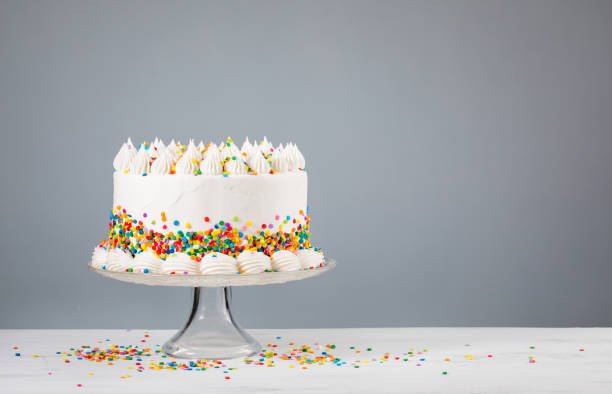 Birthday Cake with Sprinkles White Birthday cake with colorful Sprinkles over a neutral gray background. cake stock pictures, royalty-free photos & images
