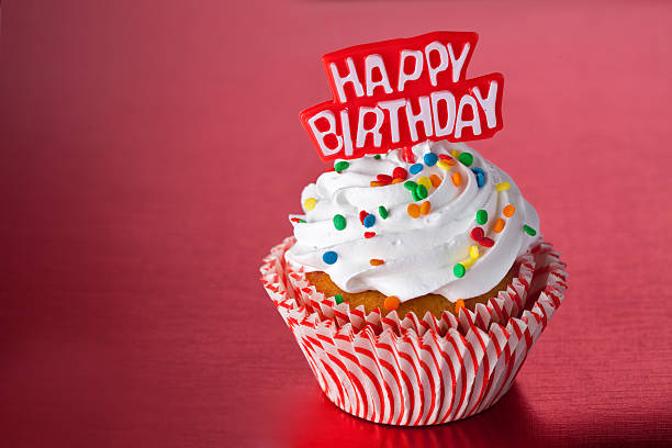 Birthday cupcake with colored sprinkles in a red background stock photo