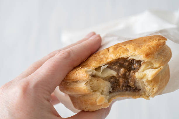 Bite Out of Mince Pie Close Up of  a Take Away Mince Pie with a Bite Out of It in a Paper Bag over a White Background meat pie stock pictures, royalty-free photos & images