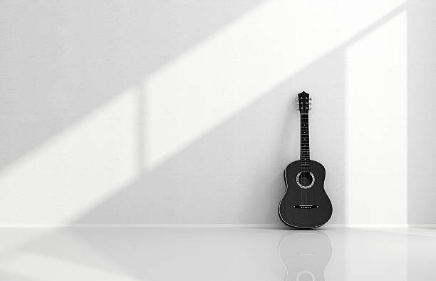 Black acoustic guitar in a white room stock photo