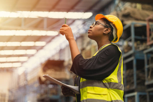 Black African professional women worker working count checking inventory production stock control in business factory  industry warehouse waring engineer suit and helmet for safety stock photo