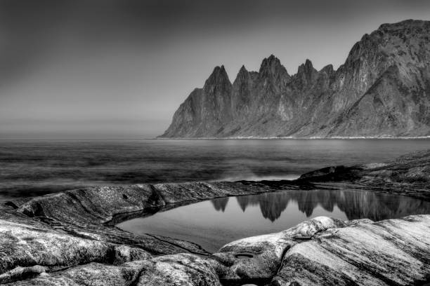 Black and White Image of Norwegian Coastline, With Mountains Reflected in Tidepool stock photo