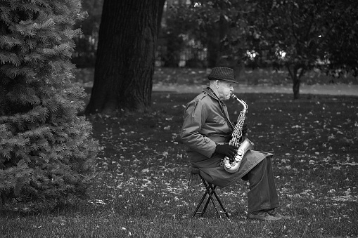 RIGA, LATVIA - JULY, 2017: Black and white image of old man plaing saxophone in the park