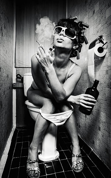 Black and white photo of a woman sitting on the toilet stock photo