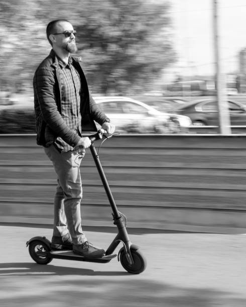 Black and white photo of young man riding electric scooter stock photo