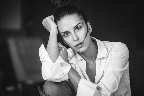 Black and white portrait of a pensive young woman in white shirt stock photo
