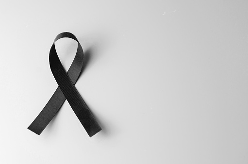 Black awareness ribbon on gray background. Mourning symbol, copy space.