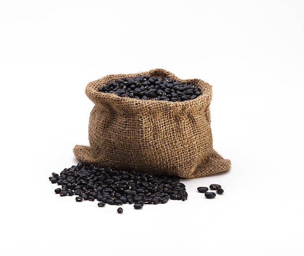 Black beans arranges in the sack isolated on white background stock photo