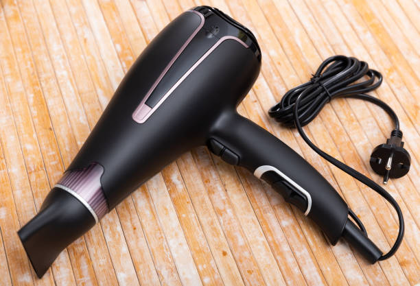 Black blow dryer on wooden surface stock photo