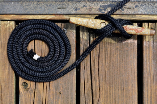 black rope securing boat to wooden dock