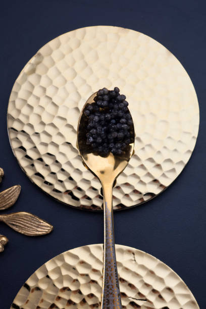 black caviar on a golden spoon in a beautiful black and white composition A real black caviar on a golden spoon in a beautiful black and white composition. Black plan, top view roe stock pictures, royalty-free photos & images