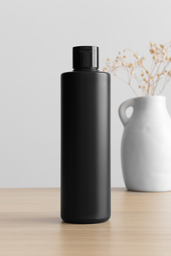 Black cosmetic lotion bottle mockup with a gypsophila on the wooden table.
