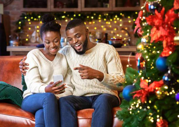 black couple making video call with smartphone, congratulating their family - smartphone christmas imagens e fotografias de stock