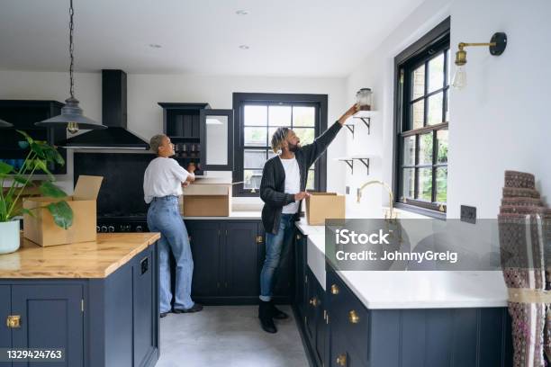 Black couple unpacking boxes in Shaker-style kitchen