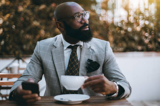 A black elegant guy in a street cafe stock photo