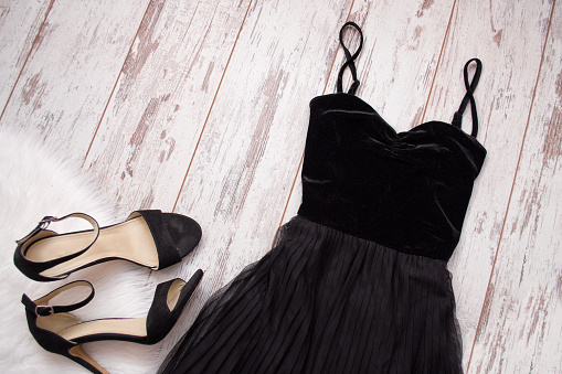 Black evening dress and shoes on a wooden background. Fashion concept. Top view, space for text