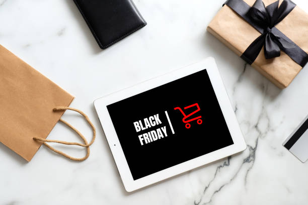 Black friday sale concept. Tablet pad with sign "Black friday", gift box, shopping bag on marble table. Flat lay, top view, overhead  black friday shoppers stock pictures, royalty-free photos & images