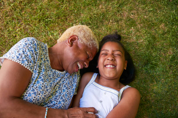 svart flicka och mormor liggande på gräset, overhead närbild - retirement overview bildbanksfoton och bilder