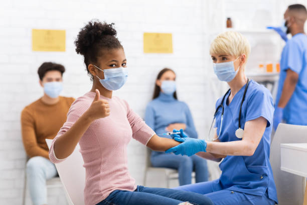 czarna dziewczyna gesturing kciuki-up odbieranie coronavirus szczepionka wstrzyknąć w szpitalu - covid vaccine zdjęcia i obrazy z banku zdjęć