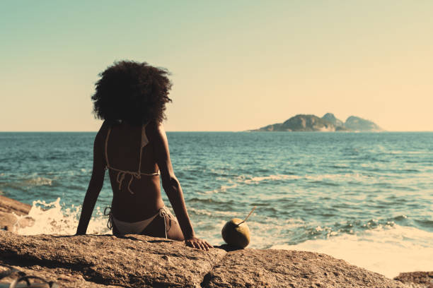 Black girl on the beach, teal water stock photo