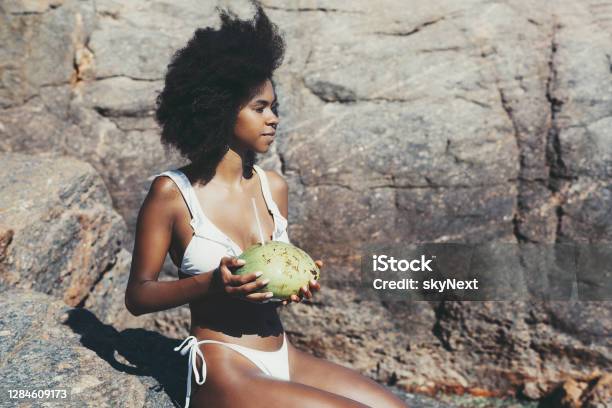 Black girl with coconut on the beach