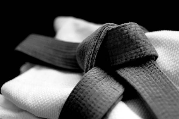 Black judo, aikido, or karate belt on white judo uniform Black judo, aikido or karate belt on white budo gi. Concept is applicable to sports, business or educationBlack judo, aikido, or karate belt on white judo uniform bushido lifestyle stock pictures, royalty-free photos & images