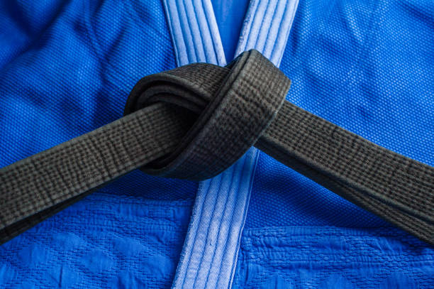 Black judo, aikido, or karate belt, tied in a knot Black judo belt tied in a knot layng on blue judogi bushido lifestyle stock pictures, royalty-free photos & images
