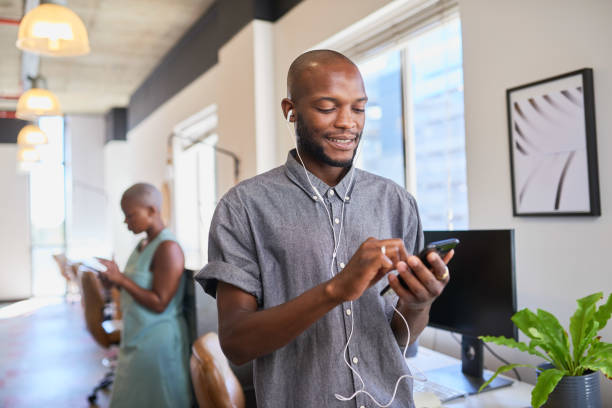 A Black man connects to a remote meeting call with earphones in the office stock photo
