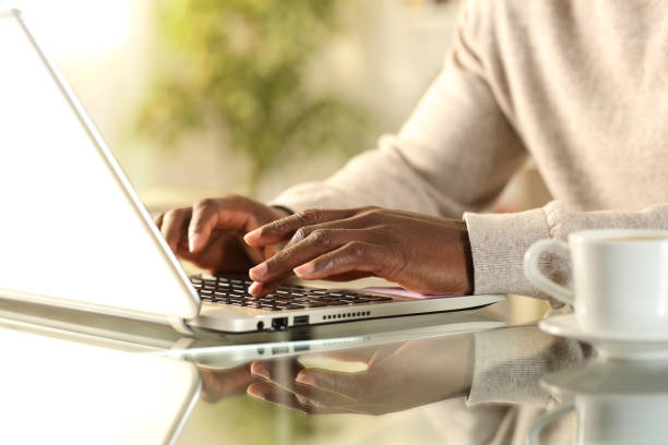 Black man hands typing on a laptop at home Close up of black man hands typing on a laptop sitting on a desk at home typing on laptop stock pictures, royalty-free photos & images